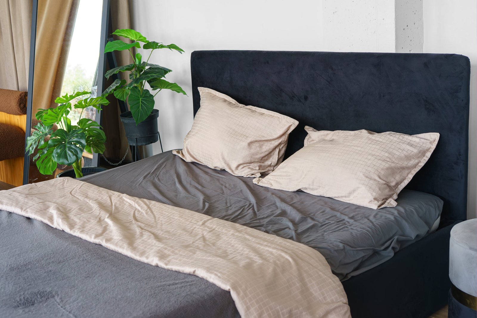 Cozy bedroom setting with pillows and beige and gray cotton soft on black headboard background. Bedroom home interior with comfortable bed, relax zone, sleeping area.