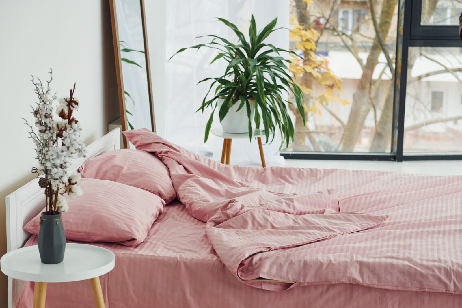 Pink colored bed. Interior and design of beautiful modern bedroom at daytime.